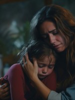 صورة لطفلة تخفي شيئا عن أمها وهي تحتضنها