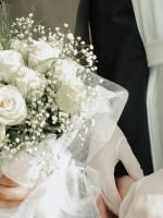 زوج يمسك بيد زوجته في حفل الزفاف ويمسك بيده الأخرى باقة زهور الفرح