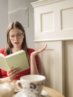 قتاة تقرأ رواية رعب وتبدو منفعلة معها