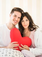 زوجان يمسكان قلباً أحمر ويبتسمان