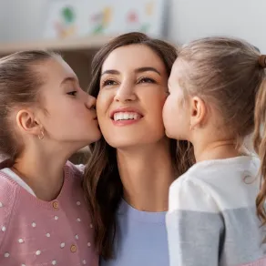 صورة لأم تتلقى قبلتين من بنتيها