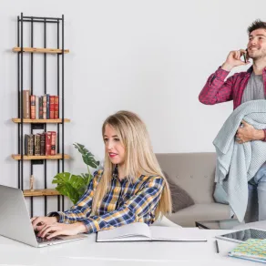 زوج يحمل ابنه في محاولة لمساعدة زوجته حتى تستكمل عملها عبر جهازها المحمول، فالزوجة يمكنها أن تطلب مساعدة زوجها لتحقيق التوازن بين العمل والحياة العائلية  - المصدر: freepik زوج يحمل ابنه في محاولة لمساعدة زوجته حتى تستكمل عملها عبر جهازها المحمول