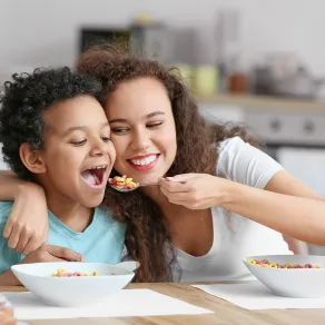 أم تُطعم طفلها أطعمة صحية تقوّي مناعته صورة لأم تُطعم طفلها بمرح