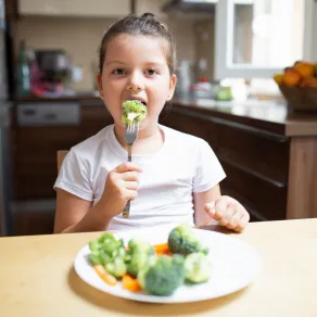 اهتمي بتقديم البروكلي والقرنبيط لطفلك صورة لطفلة تأكل زهرات البروكلي