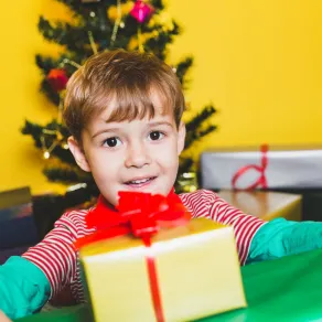 أعدي لطفلك توزيعات يقدمها للآخرين في العام الجديد صورة لطفل سعيد مع هدايا العام الجديد