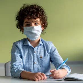 يجب أن تحمي طفلك من الأمراض المعدية في المدرسة صورة لطفل يرتدي كمامة في المدرسة