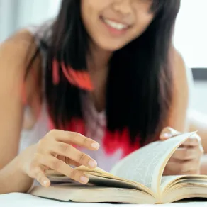 فتاة تقرأ كتابا وهي تبتسم بسعادة