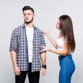 زوج يبدو مستاء وزوجته تعاتبه وهي تضع يدها على كتفه   