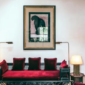 غرفة معيشة مع أريكة خشبية فخمة ذات وسائد باللون الأحمر الداكن المعروف بدم الغزال غرفة معيشة مع أريكة ذات وسائد باللون الأحمر الداكن