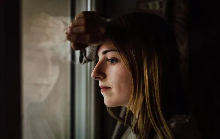 فتاة تضع رأسها على النافذة تبدو مترددة وفي حيرة من أمرها