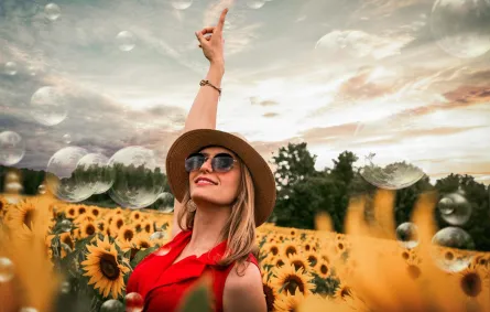 شابة واثقة بنفسها ترتدي نظارة شمسية ترفع يدها للسماء بسعادة