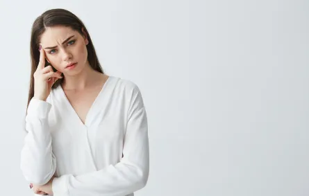 فتاة تضع أحد أصابعها على جبهتها من الجانب يبدو عليها ملامح القلق