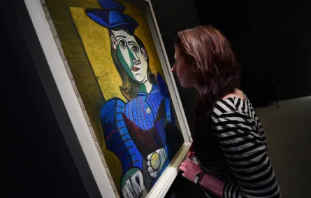 زائرة تنظر إلى لوحة "تمثال نصفي لامرأة ترتدي قبعة زرقاء" خلال معرض بابلو بيكاسو "التجلي" في المتحف الوطني المجري في 20 أبريل/ نيسان 2016 في بودابست. المصدر: (Photo by ATTILA KISBENEDEK / AFP)