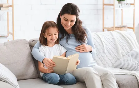 الأم تقرأ والابنة والجنين يستمعان