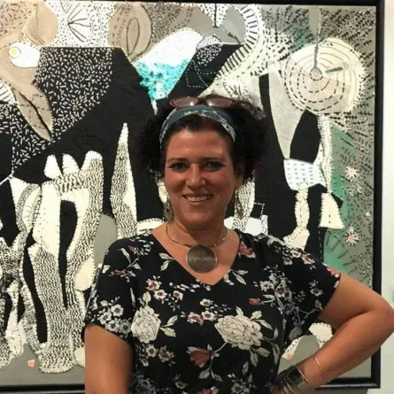 فنانة تقف أمام إحدى لوحاتها