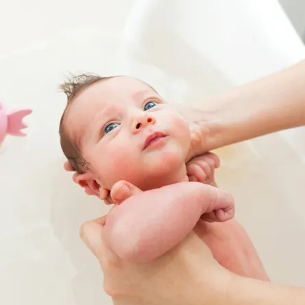 صورة  لأم تقوم بتحميم طفلها