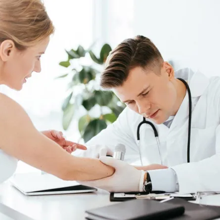 طبيب جلدية يفحص العلامات في يد المريضة