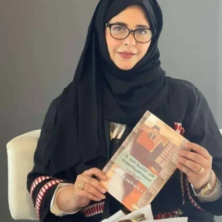 الدكتورة رانية خوقير مع كتابها عن الأزياء التراثية لنساء قبيلة حرب 