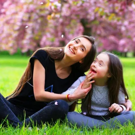 صورة لأم تشجع طفلتها من ذوي الاحتياجات الخاصة