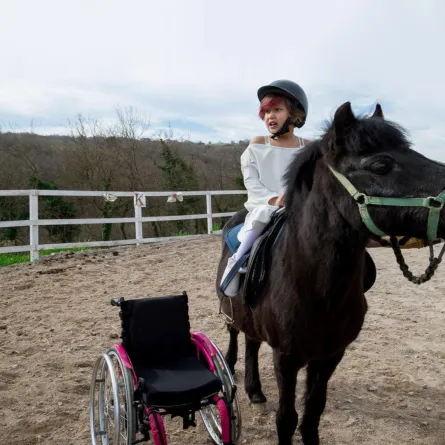صورة لطفلة من ذوي الهمم تمتطي جواداً