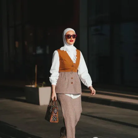 دلال الدوب ببدلة كاروهات ببليزر بدون أكمام مع بلوزة بيضاء واسعة 