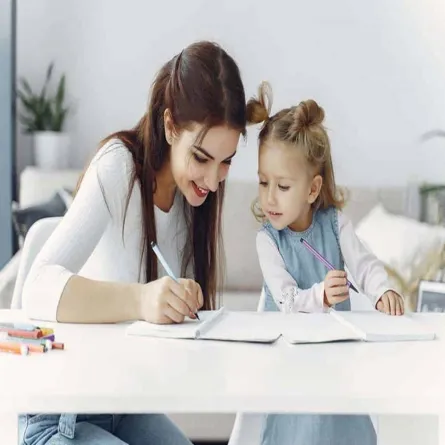 صورة لأم تقوم بتدريب طفلها على الكتابة 