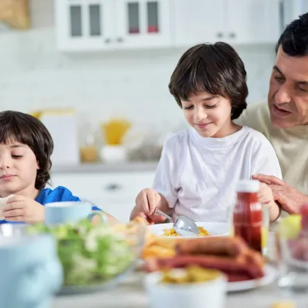 صورة لأب يوجه أطفاله في تناول الأطعمة المفيدة