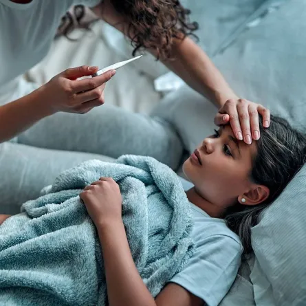 صورة لأم تقيس درجة حرارة طفلتها