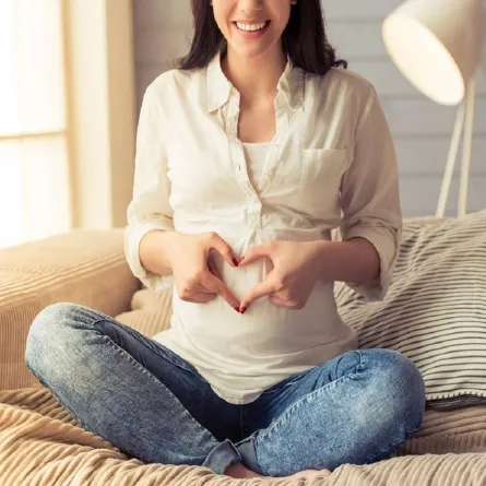 صورة لحامل تقوم برسم قلب بأيديها 