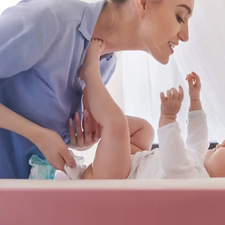 صورة لأم تغير الحفاض لطفلها