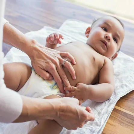 صورة لأم تقوم بتغير الحفاض لطفلها