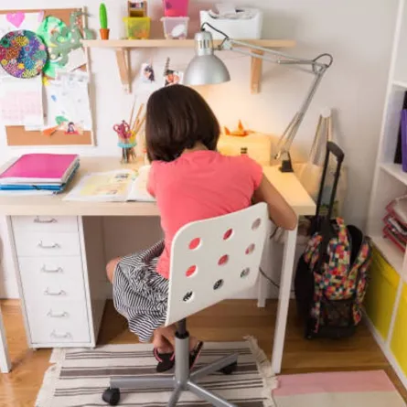 صورة لطفلة تجلس إلى مكتب الدراسة في غرفتها