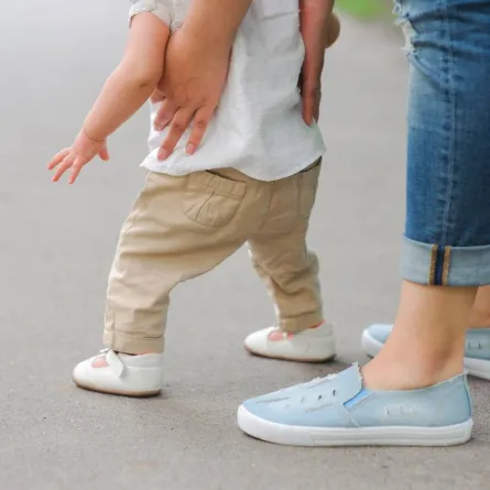 صورة لأم تساعد طفلتها على المشي