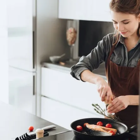 امرأة تطهو السمك في مطبخ المنزل