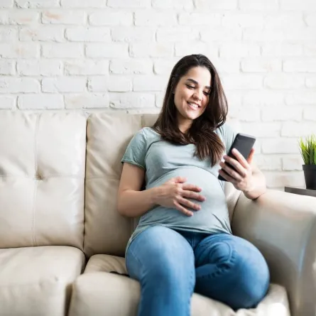صورة لامرأة حامل تنظر لشاشة الهاتف 