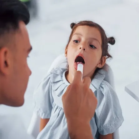 صورة لطبيب يفحص حلق طفلة