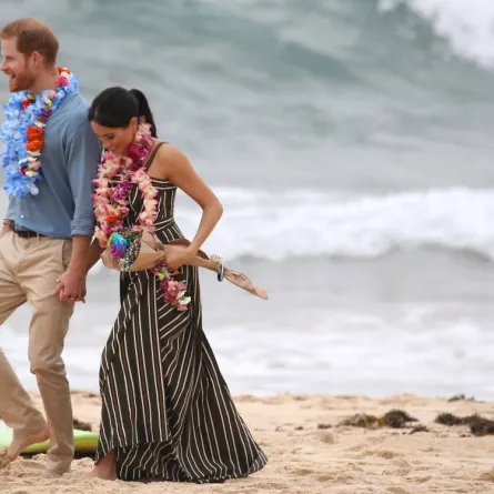 Britain's Prince Harry walks with his wife Meghan, Duchess of Sussex as they meet the local community at Bondi Beach in Sydney on October 19, 2018. British royals Harry and Meghan kicked off their shoes and donned tropical garlands on October 19, as they hit Sydney's famed Bondi beach for the latest stop on their Australian tour. DAVID MOIR / AFP