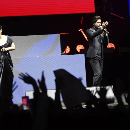 Indian actor, film producer, and television personality Shah Rukh Khan talks to his fans as Indian actress Kajol Devgan commonly known as Kajol waves with her hand at the corniche during the opening of the Red Sea International Film Festival, in Jeddah, Saudi Arabia, on December 1, 2022. AMER HILABI / Red Sea Film Festival