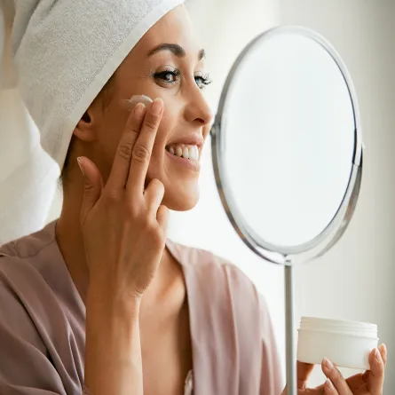 صورة لامرأة تضع كريم تجميلي على وجهها