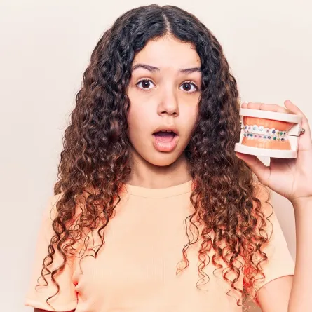 صورة لطفلة تمسك بتقويم الأسنان