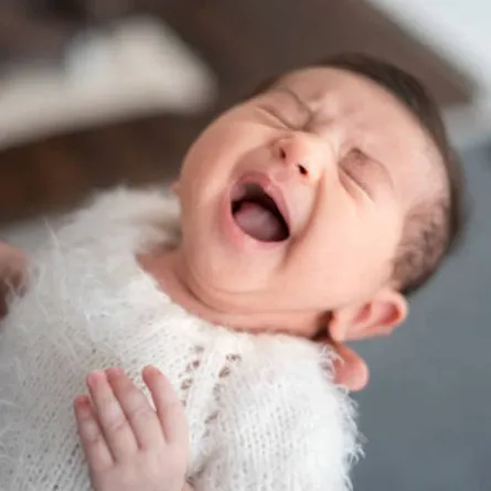 صورة لرضيع يبكي بين يدي أمه