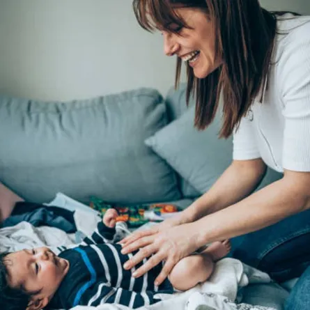 صورة لأم تقوم بتغيير حفاض طفلها