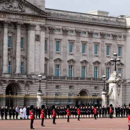 Members of staff wait outside Buckingham Palace as the Procession following the coffin of Queen Elizabeth II, on the State Gun Carriage of the Royal Navy, passes on its way to Wellington Arch in London on September 19, 2022, after the State Funeral Service of Britain's Queen Elizabeth II. Niklas HALLE'N / AFP
