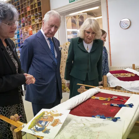 King Charles III (C) and the Britain's Camilla, Queen Consort (R) look at their throne seat covers during a visit to the Royal College of Needlework at Hampton Court Palace in East Molesey, south-west London on March 21, 2023. Kirsty O'Connor / POOL / AFP