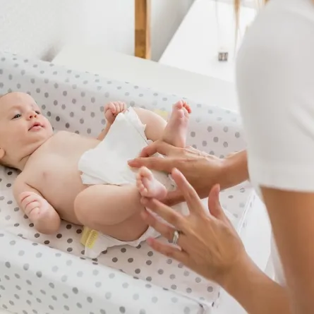 صورة لأم تقوم بتغيير حفاض طفلها