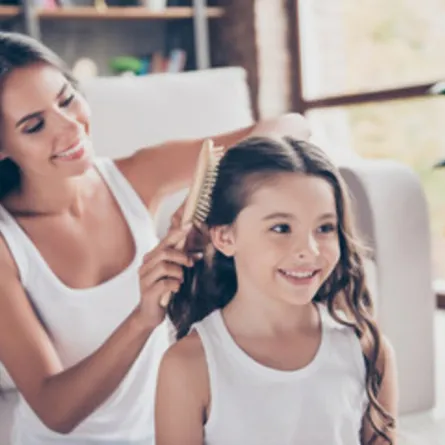 صورة لأم تستمتع بجمال شعر طفلتها