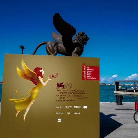 تمثال لأسد مجنح يرمز إلى مدينة البندقية، والملصق الرسمي لمهرجان البندقية السينمائي الدولي الـ 79 (A sculpture of a winged lion, which symbolizes the city of Venice, and the official poster of the 79th Venice International Film Festival). مصدر الصورة: Andreas SOLARO / AFP