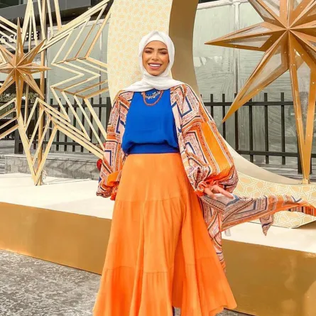 منة السُني بتنورة طويلة باللون البرتقالي