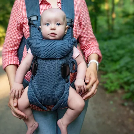 صورة لأم تحمل طفلها بشيالة الاطفال