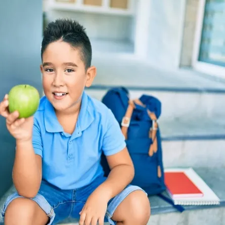 صورة لطفل يحمل تفاحة خضراء